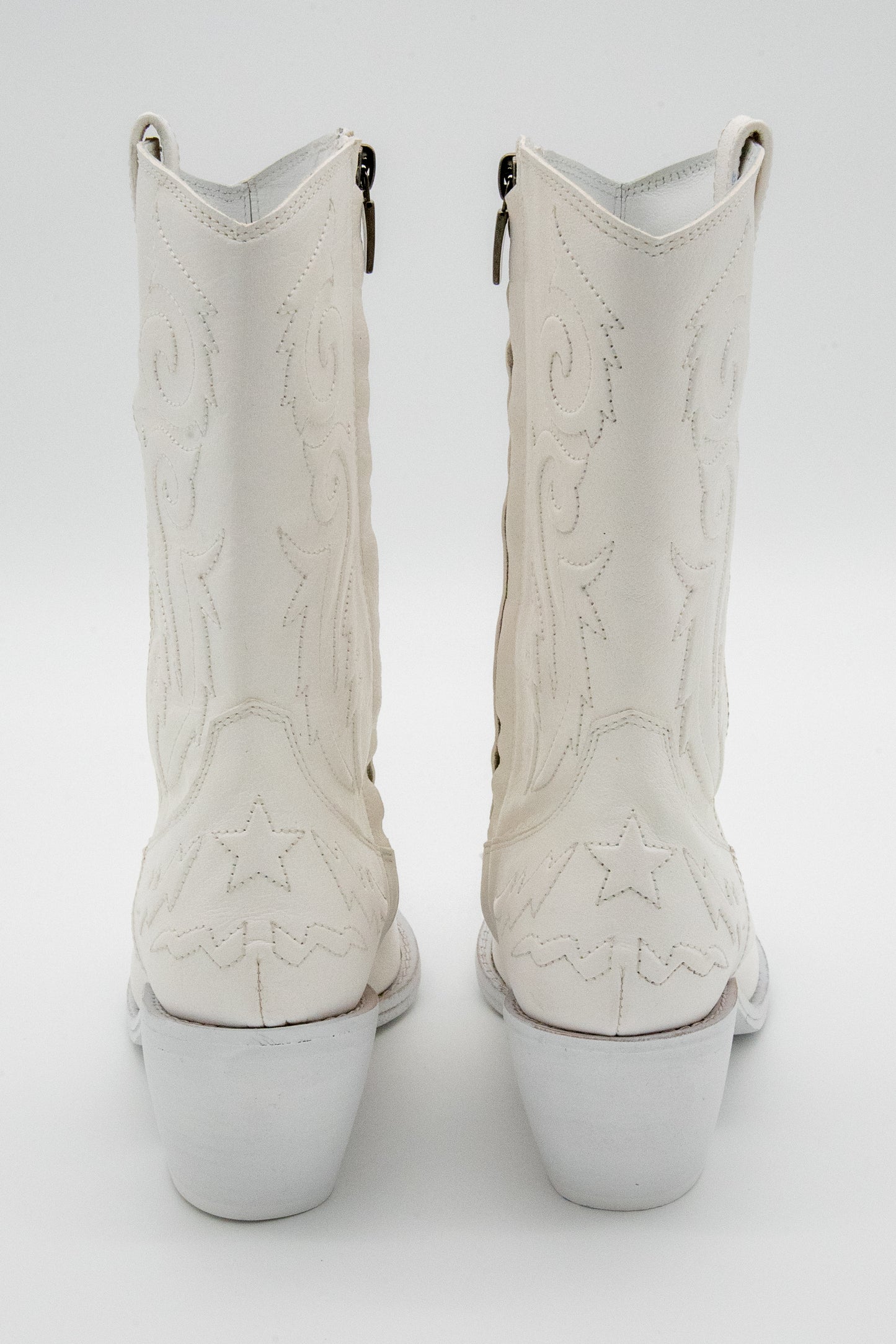 White cowboy boots with star stitching on a white background