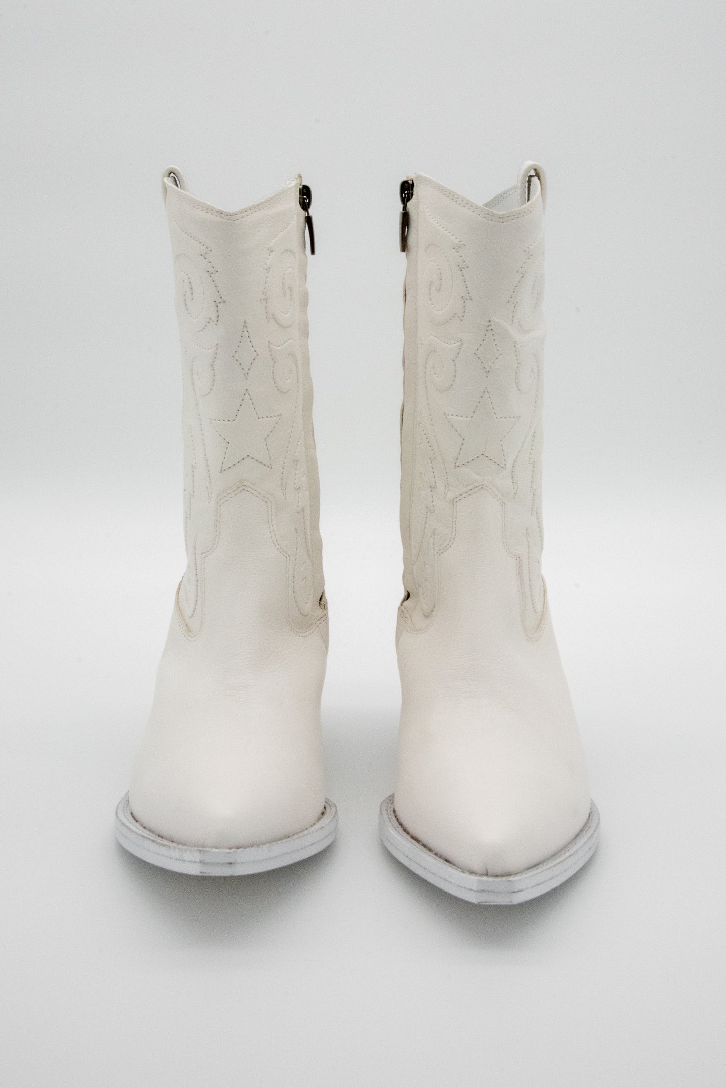 Pair of white mid-calf cowboy boots on a white background.